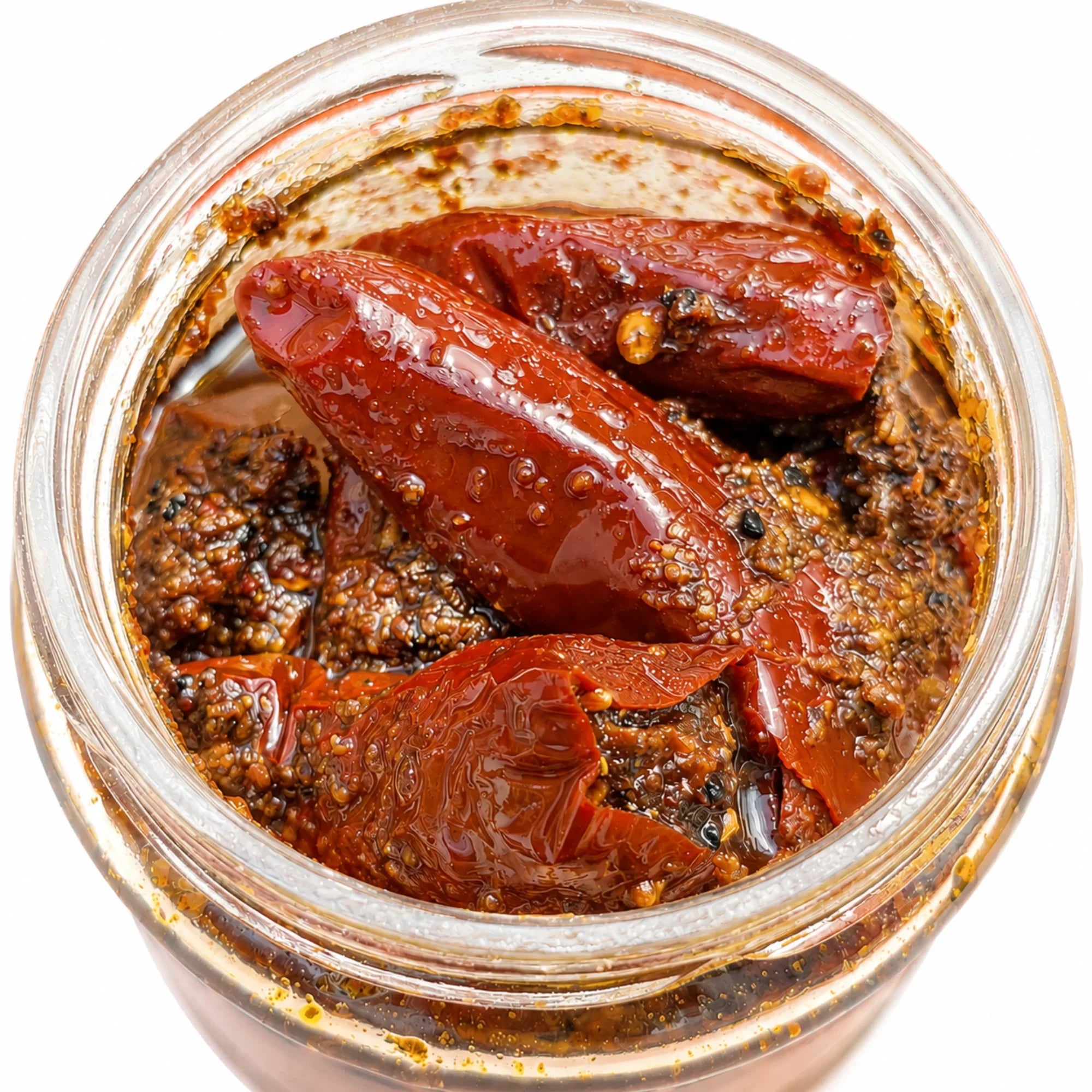 Handmade red chili pickle in glass jar with mustard oil, spices, and whole chilies, crafted by rural artisans.