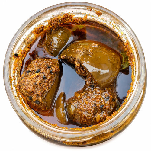 Close-up of a glass container with sun-dried mango pickle. Piece of Mango pickle are visible.  
